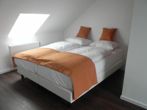 a white bed with an orange blanket on it at Hotel - Restaurant Uit De Kunst in Vijlen