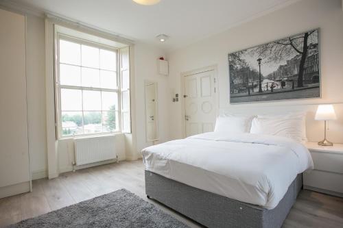 una camera da letto bianca con un letto grande e una finestra di Hatch Street St Stephen's Green Apartments a Dublino