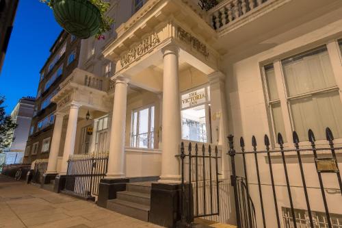 a white building with columns and a fence at Victoria Inn London in London