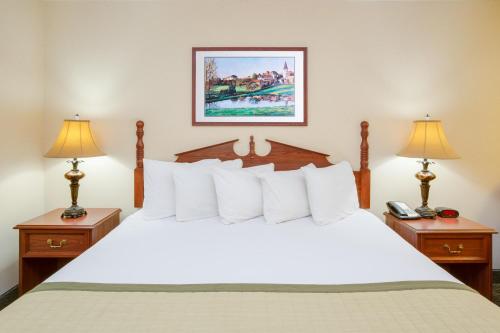 a bedroom with a white bed with two nightstands and two lamps at Baymont by Wyndham Ozark in Ozark