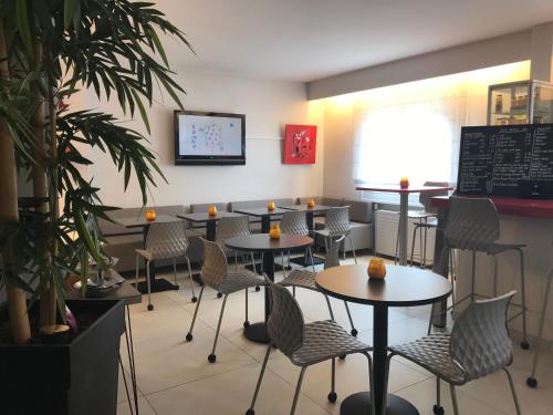 a restaurant with tables and chairs in a room at The Originals City, Hôtel Dau Ly, Lyon Est in Bron