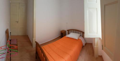 an orange bed in a small room with a window at Olive Street House in Coimbra
