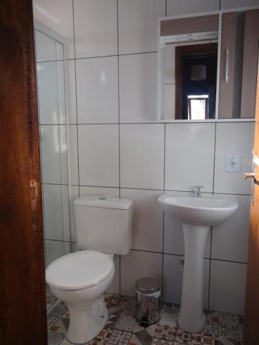a white bathroom with a toilet and a sink at Long Life Campeche-Pousada in Florianópolis