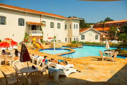 un grupo de personas sentadas en sillas junto a una piscina en Hotel Fazenda Fonte Colina Verde, en São Pedro