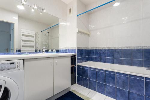une salle de bains bleue et blanche avec une baignoire et un lave-linge. dans l'établissement Les Jardins de Nazareth, à Montpellier