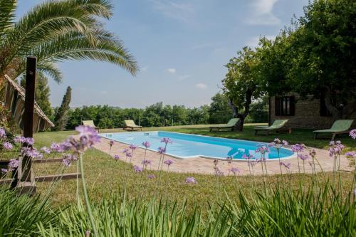 una piscina in un giardino con fiori viola di Agriturismo La Vecchia Fonte a Castelbellino