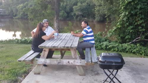 three people sitting at a picnic table with a grill at Red Carpet Inn Kinston in Kinston