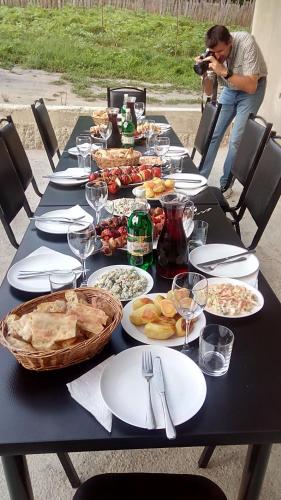a table with plates of food and a man taking a picture at Roza's guest house in Mestia