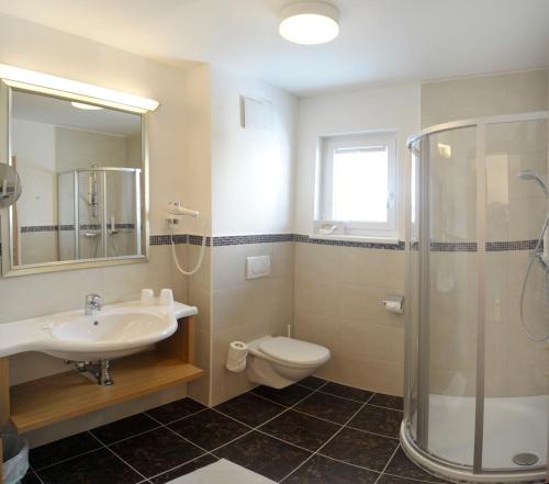 a bathroom with a sink and a toilet and a shower at Panoramahotel Gürtl in Haus im Ennstal