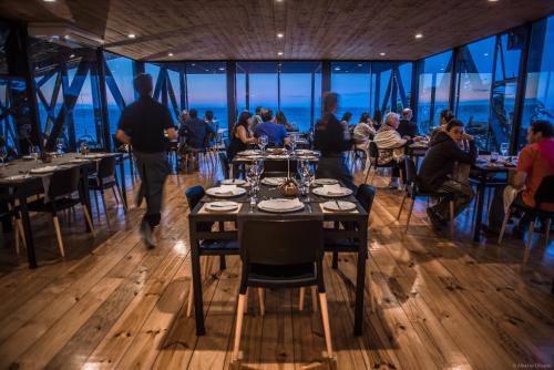 a restaurant with people sitting at tables in a room with windows at Hotel Puerto Viejo Llico in Llico