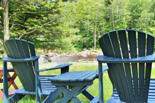 two green chairs sitting on a bench in the grass at Hungry Trout Resort in Wilmington