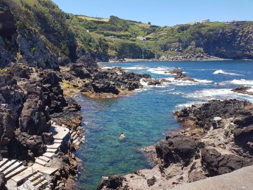 a person swimming in a river on a rocky beach at Quinta Rico in Quatro Ribeiras