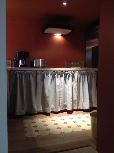 a kitchen with white curtains and a table with a rug at Le voyage d'UBUNTU in Heiligenstein