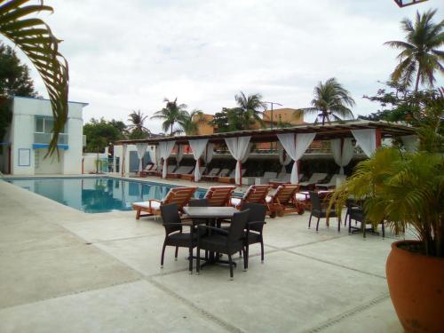 a patio with tables and chairs next to a pool at Hotel Santa Cruz Huatulco in Santa Cruz Huatulco