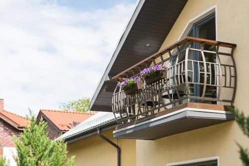 a balcony with purple flowers on a house at Rasos Vila in Palanga