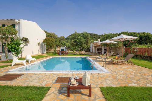 a swimming pool with a table and chairs in a yard at Skales Villas in Almiros Beach