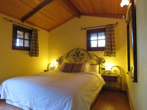 a bedroom with a white bed with two windows at Villa Ayagaures in Los Palmitos