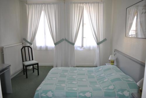 een slaapkamer met een bed, een stoel en ramen bij Grand Hotel de l'étoile in Courtenay