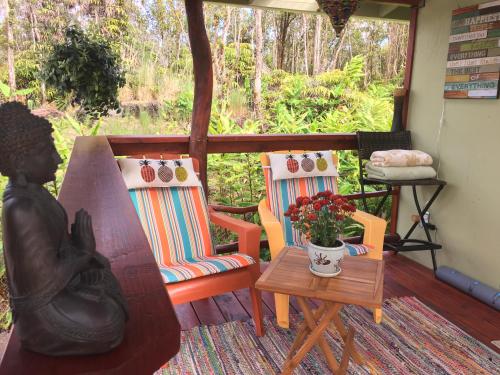 a porch with two chairs and a table with a vase of flowers at Rainforest Eco Cabin in Volcano