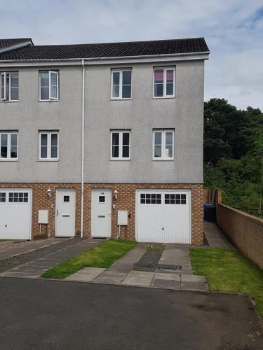 a brick building with four white garage doors at Livingston 4 bedroom townhouse in Livingston