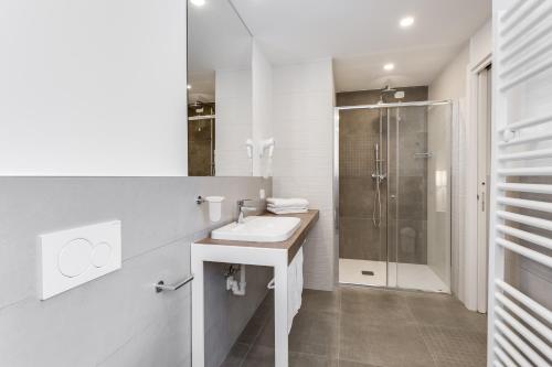 a white bathroom with a sink and a shower at Hotel Europa in Garda