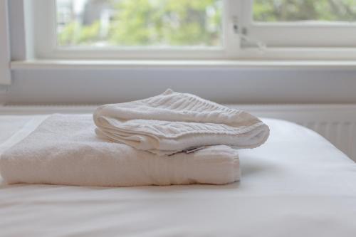 Una pila de toallas encima de una cama en Victoria Inn London, en Londres