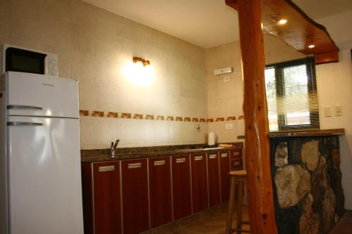 a kitchen with a white refrigerator and wooden cabinets at Cabañas Alpendorf in Villa General Belgrano