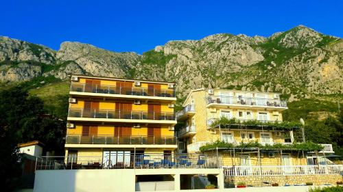 two tall buildings in front of a mountain at Apartments Dragišić in Sveti Stefan