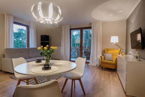 sala de estar con mesa, sillas y sofá en Sosnowe Tarasy, en Mielno
