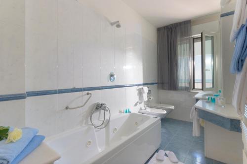 y baño con 2 aseos, bañera y lavamanos. en Hotel Il Timone, en Porto San Giorgio