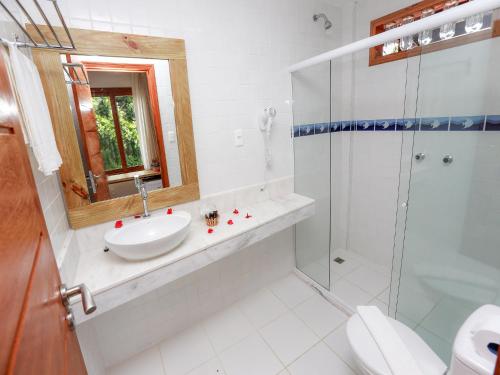 uma casa de banho branca com um lavatório e um chuveiro em Pousada Paraíso do Forte na Praia do Forte