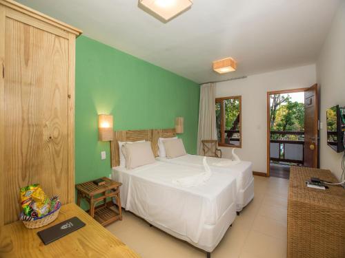 um quarto com uma cama branca e uma parede verde em Pousada Paraíso do Forte na Praia do Forte