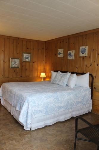 1 dormitorio con 1 cama grande y paredes de madera en Town & Beach Motel en Falmouth