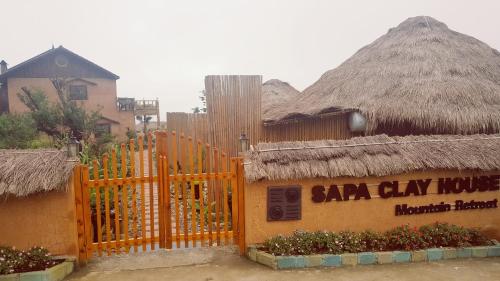 a sara clay house with a fence and a building at Sapa Clay House - Mountain Retreat in Sa Pa