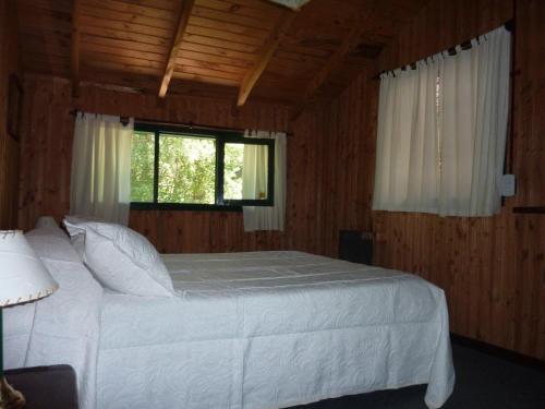 a bedroom with a white bed and a window at Cabañas Las Lavandas in El Bolsón