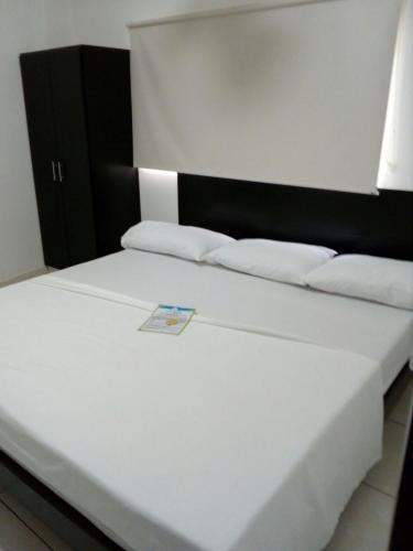 a bed with white sheets and a book on it at Hotel Centro Real in San Gil