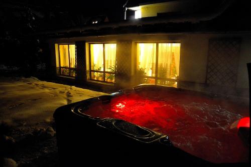 a hot tub filled with red water in front of a house at Apartamenty Willa Anna in Poronin