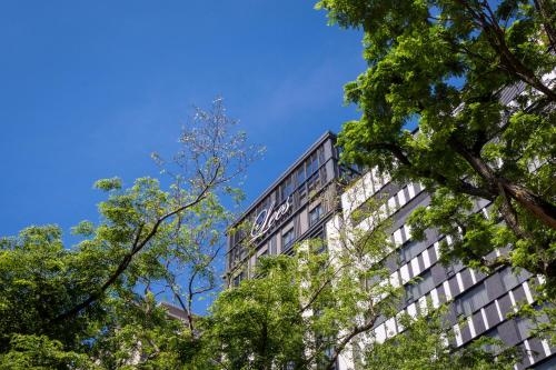 un edificio alto con árboles delante de él en Park Lees Hotel, en Kaohsiung