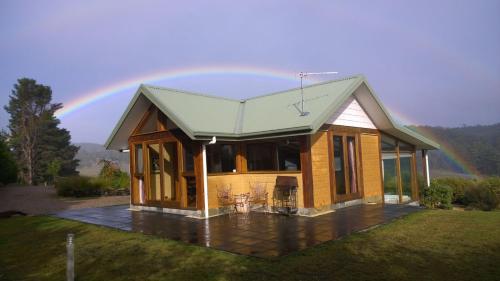 a house with a rainbow in the background at Shanleys Huon Valley in Glendevie