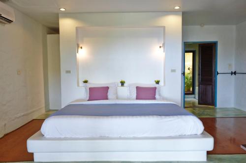 a bedroom with a large white bed with pink pillows at Vacation Village Phra Nang Lanta - SHA Extra Plus in Ko Lanta