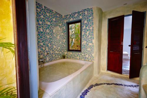 a bath tub in a bathroom with blue and white wallpaper at Vacation Village Phra Nang Lanta - SHA Extra Plus in Ko Lanta