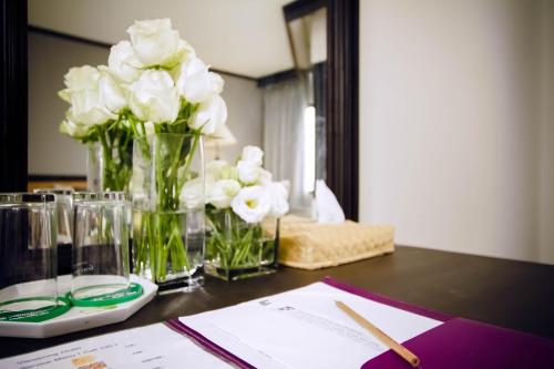a table with white flowers in vases on it at Fortune View Khong Hotel Nakhon Phanom in Nakhon Phanom