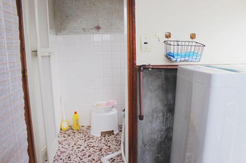 a small bathroom with a small refrigerator in it at Guesthouse Ogawaya in Tanabe
