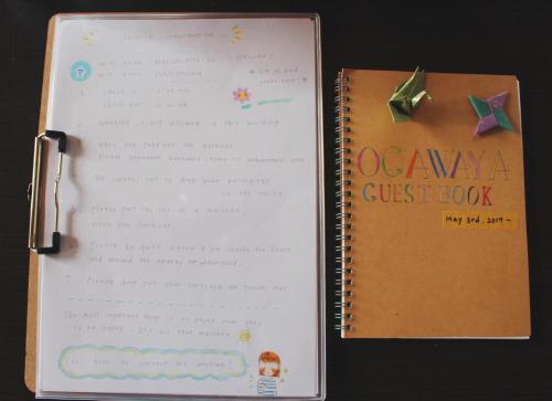 a notebook with a qawarma guest book next to a book at Guesthouse Ogawaya in Tanabe