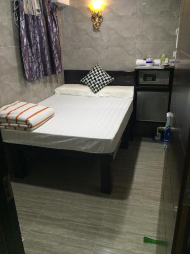 a small bed with white sheets and pillows on it at Victoria Inn in Hong Kong