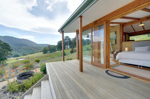a bedroom with a bed on a wooden deck at Shanleys Huon Valley in Glendevie