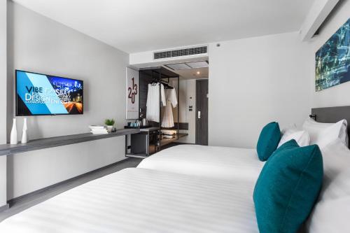 a bedroom with a white bed and a flat screen tv at Cross Vibe Bangkok Sukhumvit in Bangkok