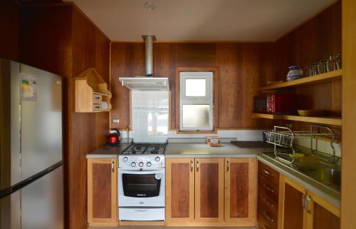 a kitchen with wooden cabinets and a stove top oven at Cabañas Alcamar in Castro