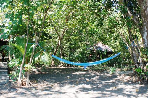 a blue hammock in the middle of trees at Sunset Cottages in Hitokalak