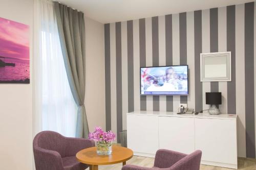 a living room with a tv on a striped wall at Boutique Hotel Intermezzo - Pag centre in Pag